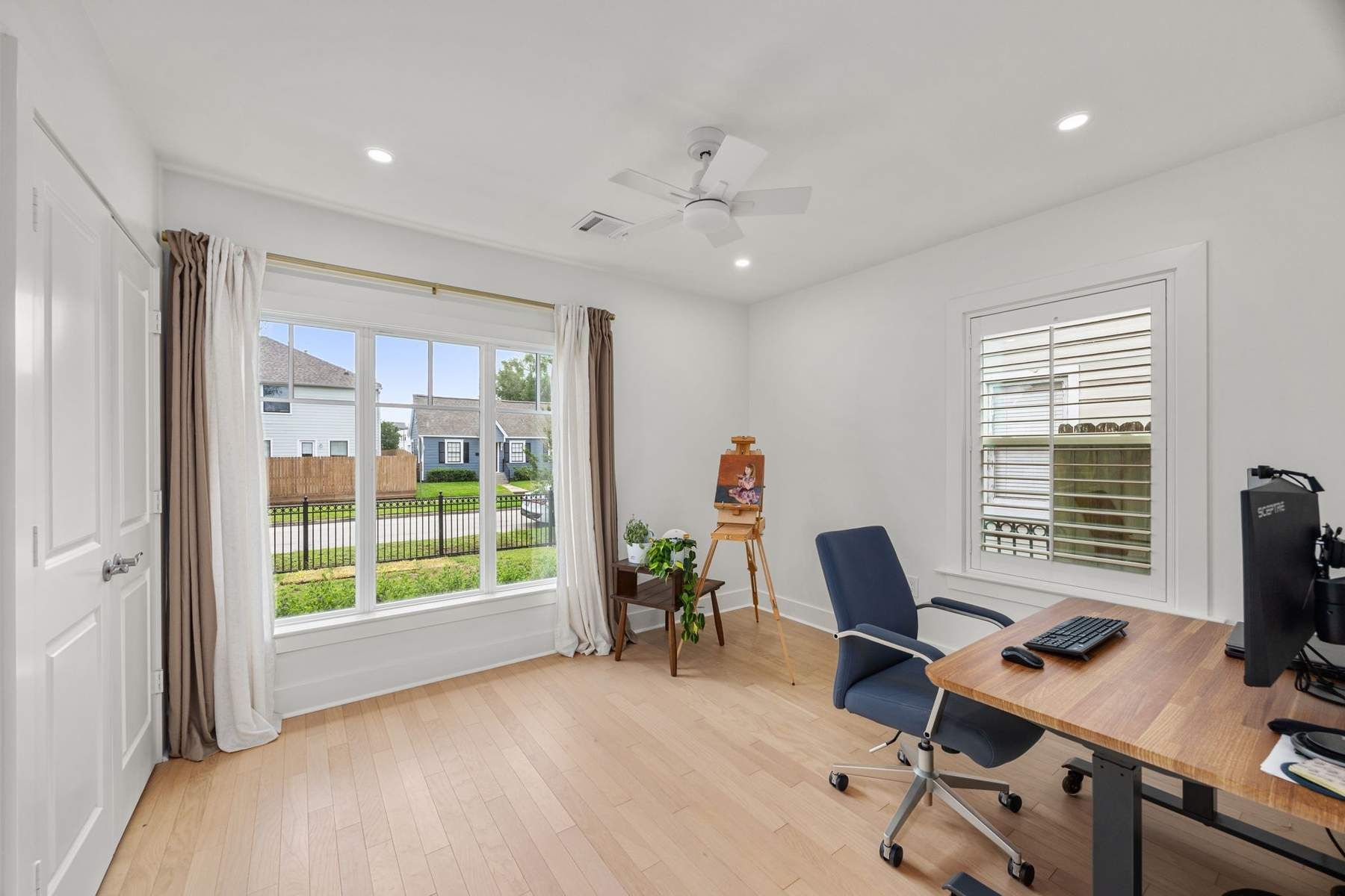 Finished front bedroom with two windows, hardwood flooring, and white trim